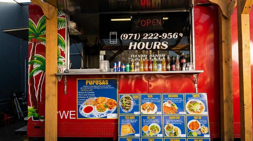 Red food truck with menu boards, drinks, and an 'OPEN' sign in the service window.